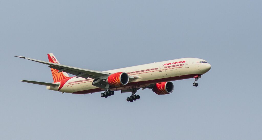 Air India Boeing 777 aircraft captured mid-flight against a clear blue sky, showcasing its design and logo.