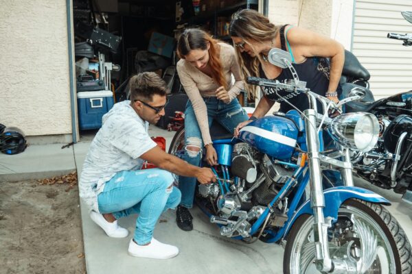Family members enjoy bonding time while working on a blue motorcycle together in the garage.