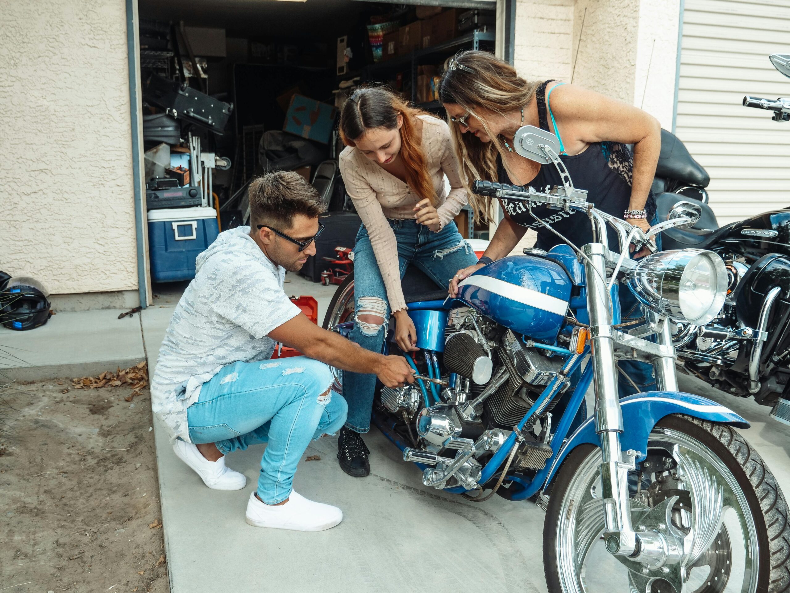 Family members enjoy bonding time while working on a blue motorcycle together in the garage.